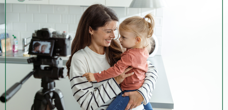 An adult holding a small child stands near a camera on a tripod in a kitchen, with a “TFO Life Academy” logo in the corner.